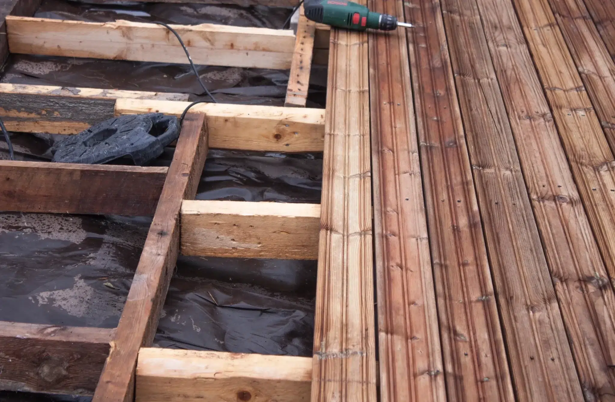 Close-up of new deck boards being fastened over a rebuilt frame